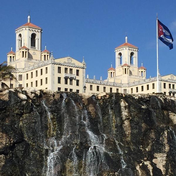 Spanish Style building on top of waterfall cliff with Cuba Flag