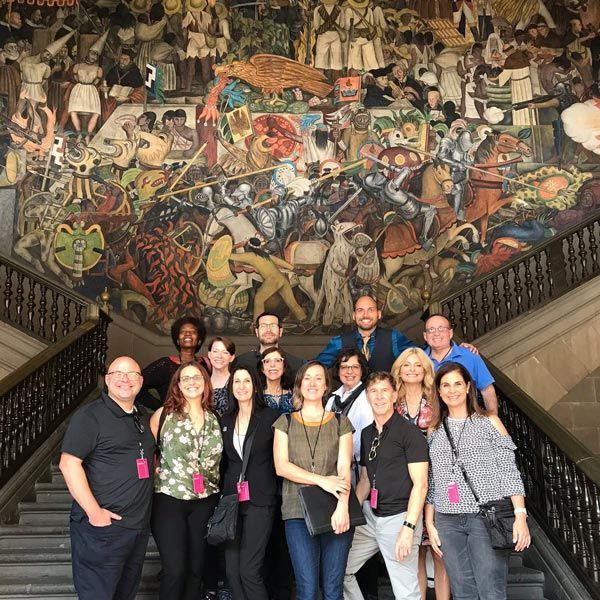 Group of attendees in staircase with fantastical painted mural in background