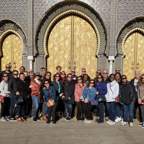 group of attendees in front of oversided golden doors