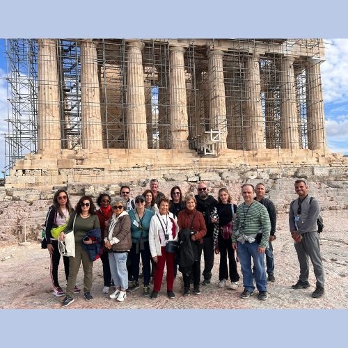 Group attendees standing before a Greek landmark