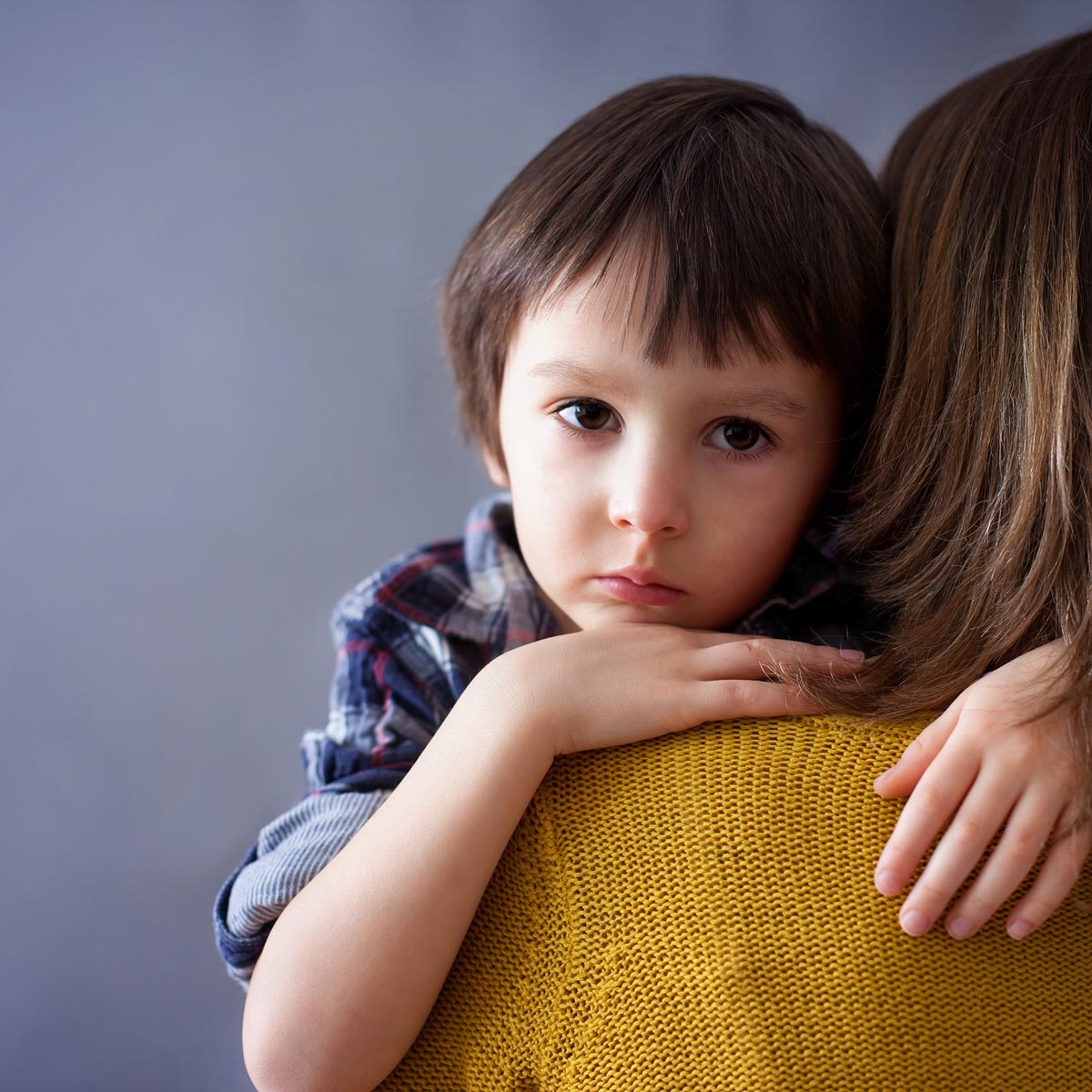 view of a caregiver from behind holding a child over their shoulder in a conforting way