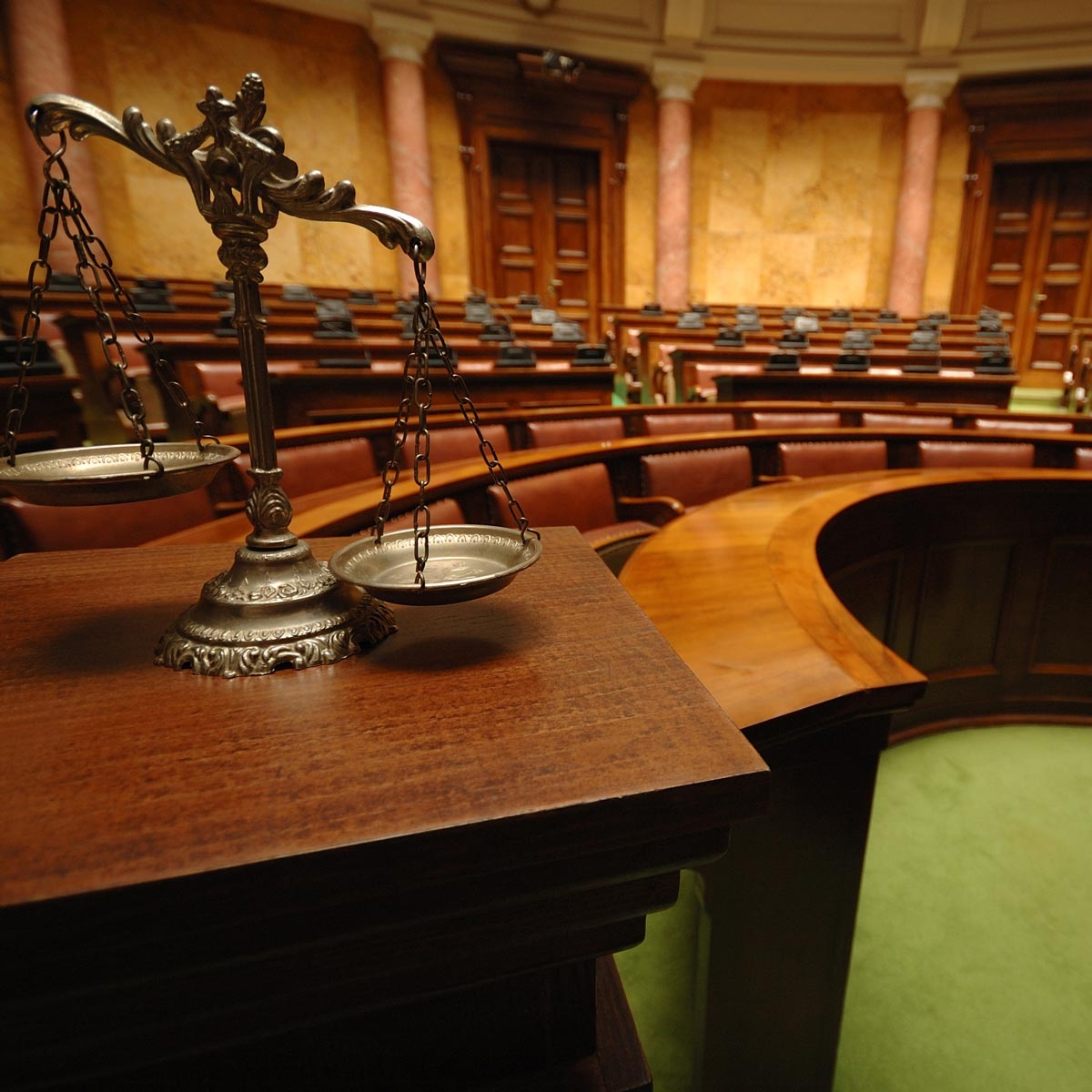 empty jury box in background with scales of justice in foreground