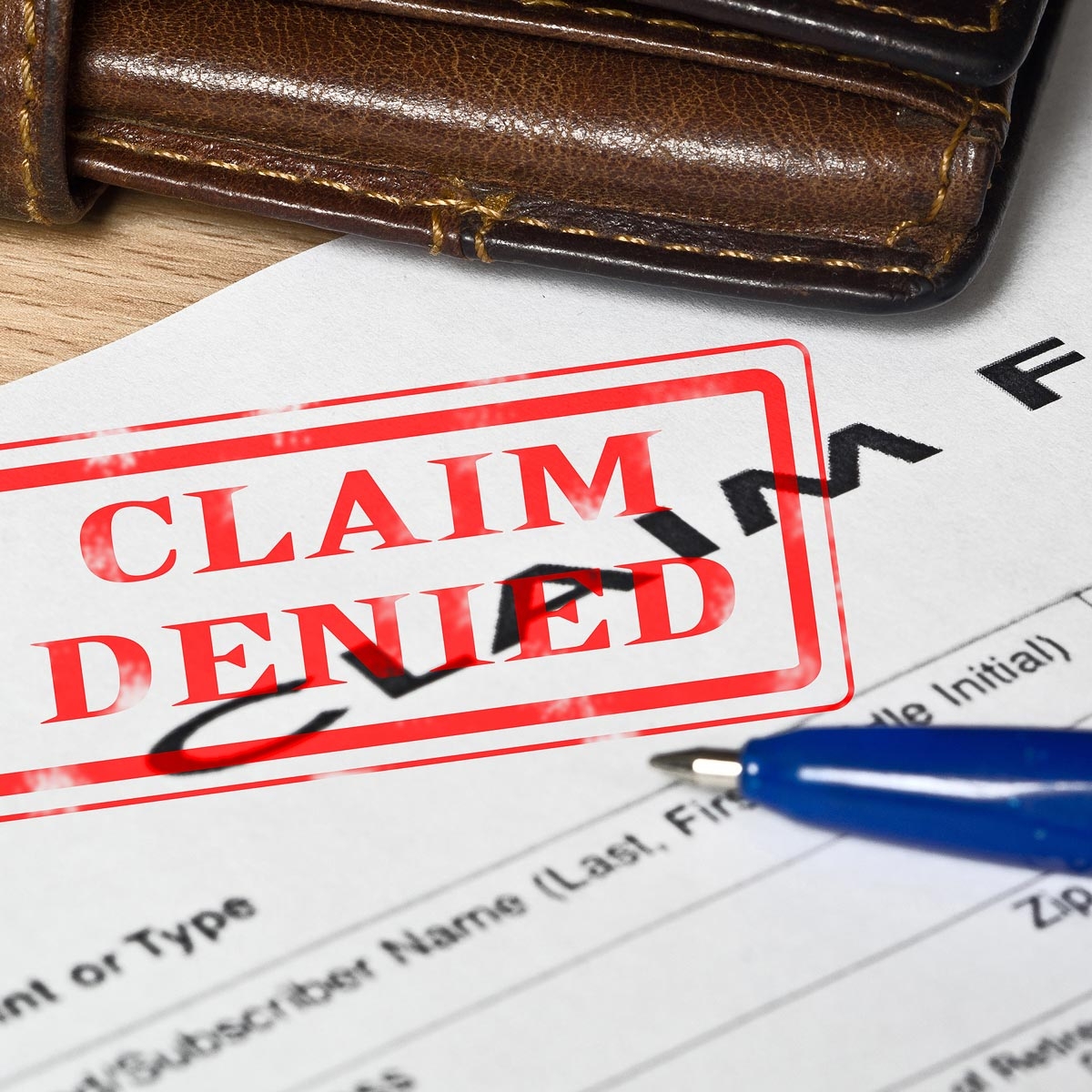 close up of insurance claim form with large 'claim denied' stamped on it