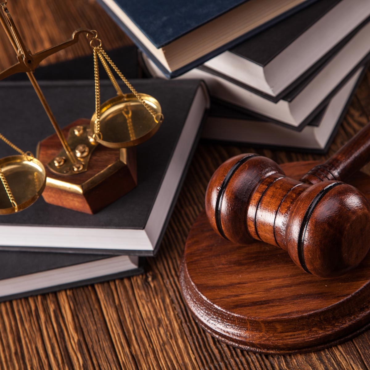 stacks of law books with small scales of justics and gavel in foreground