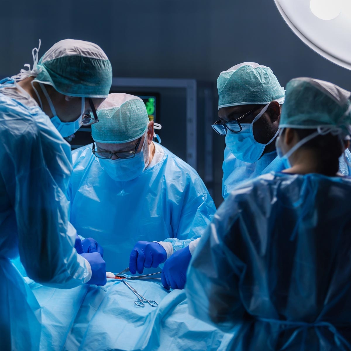 group of surgeons in scrubs working on a patient
